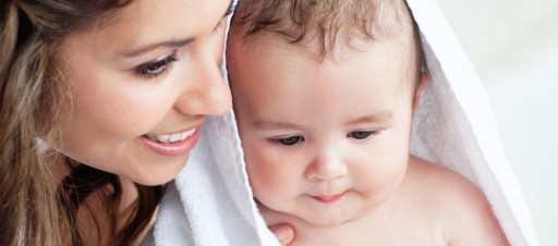 Un bebé envuelto en una toalla con su madre al lado.